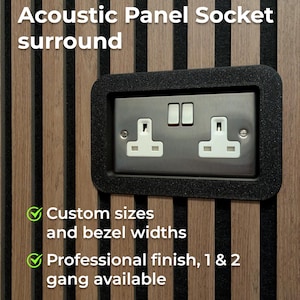 Könnte beinhalten: Akustik-Panel-Steckdosenumrandung mit schwarzem Rahmen. Das Panel hat eine silberne Steckdose mit zwei Steckdosen und zwei Schaltern. Der Hintergrund ist eine Holzwand mit vertikalen braunen und schwarzen Streifen. Der Text auf dem Bild lautet "Sondergrößen und Blendenbreiten" und "Professionelle Ausführung, 1 & 2 Gang verfügbar."