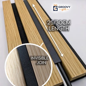 Op de afbeelding: Een paneel van licht eikenhout met een zwarte viltachterkant, voorzien van een lengte-indicator van 25/30cm en een onzichtbaar verbindingsdetail. Het paneel bevat een zwarte stroomkabel en de tekst Groovy Gift. Het ontwerp heeft drie verticale houten latten.