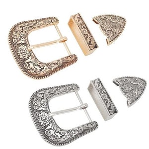May include: Two sets of belt buckles, one in gold and one in silver. Each set includes a buckle and a tip. The buckles have an ornate floral design.