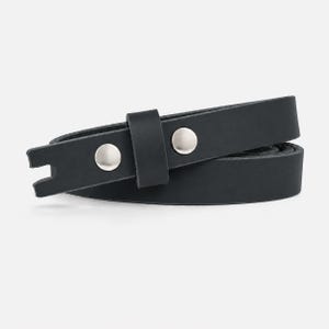 May include: A black leather belt featuring a smooth matte finish, a single matching leather keeper loop, and two polished silver-tone metal snap fasteners. The end of the belt strap is cut with a distinct notched or forked shape design.