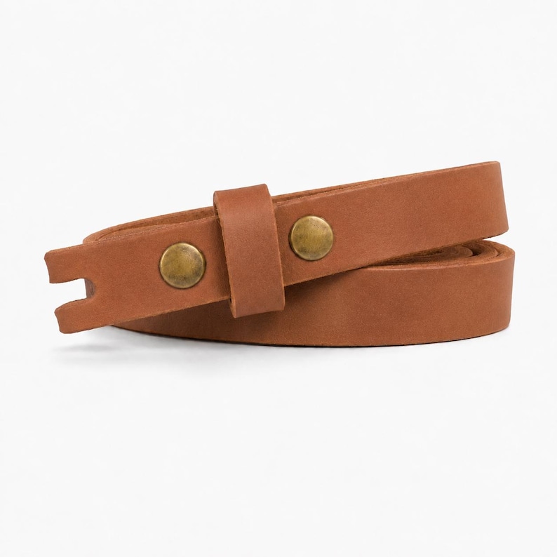 May include: A tan leather strap coiled into a loop, featuring a smooth matte finish and two circular brass-toned metal studs. The strap includes a matching leather keeper loop and a notched end, showcasing a simple and functional design.