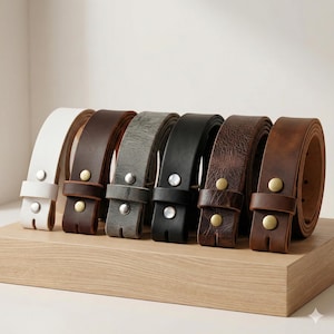 May include: A collection of leather belts in various colors, including white, brown, gray, and black, displayed on a wooden surface. Each belt has a buckle and is made of high-quality leather. The belts are arranged in a row.