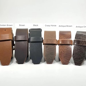 May include: Six leather belts arranged in a row, labeled Golden Brown, Brown, Black, Crazy Horse, Antique Brown, and Antique Chocolate. Each belt features a matching leather keeper loop and a pointed tip, showcasing various shades and textures.
