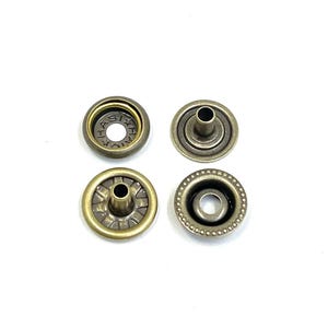 May include: Four antique brass snap fasteners arranged on a white background. Two are complete snaps, and two are the separate pieces. The snaps have a circular design with a central post and a decorative outer edge.