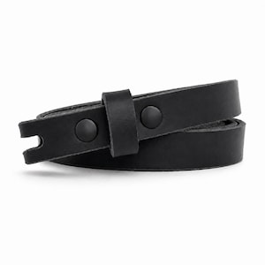 May include: A black leather belt featuring a smooth matte finish, a single leather keeper loop, and two matching black metal snap fasteners. The end of the strap has a notched cutout detail, and the belt is coiled into a circular shape.