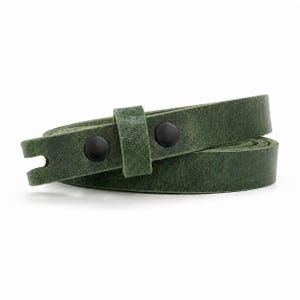 May include: A forest green leather strap coiled into a circular shape. The strap features a textured surface and is secured with two matte black metal snap buttons on a single loop, with a notched end visible on the left side of the strap.