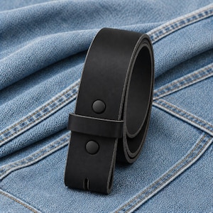 May include: A rolled-up black leather belt with two black snap closures. The belt is shown against a blue denim background. The belt is a classic accessory.