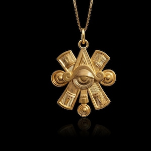 May include: A gold-colored pendant necklace with an intricate design. The pendant features an eye symbol within a geometric arrangement, with stylized elements radiating outwards. The necklace hangs against a black background, highlighting the pendant's details.