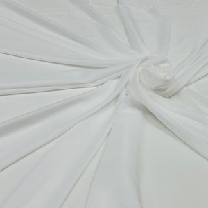 May include: White fabric draped and folded, showing the texture and drape of the material.
