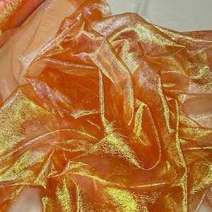 Könnte beinhalten: Orangefarbener, schimmernder, durchsichtiger Stoff mit irisierendem Effekt. Der Stoff ist gefaltet und drapiert, wodurch seine Textur und sein Glanz sichtbar werden.