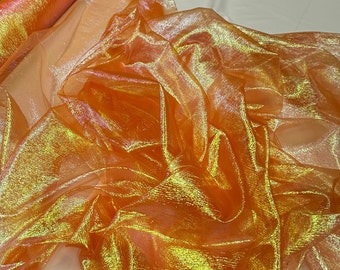 Może przedstawiać: Przezroczysty, pomarańczowy materiał o iryzującym wykończeniu z połyskiem. Materiał jest złożony i udrapowany, co ukazuje jego fakturę i połysk.