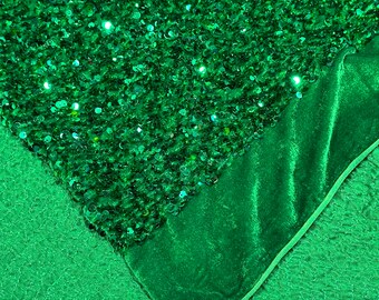 May include: A close-up of green fabric with sequins. The fabric is folded over to reveal a green velvet fabric underneath.