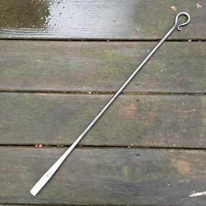 May include: A long, thin, silver metal fireplace poker with a hook on one end and a pointed end on the other.