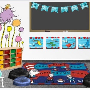 Könnte beinhalten: Eine Leseecke im Klassenzimmer mit einem blauen Schaukelstuhl, einem blauen und roten Alphabetteppich und einem Bücherregal mit Dr. Seuss-Büchern. Die Wand ist mit einem Dr. Seuss-Zitat und einer bunten Fische-Illustration dekoriert.