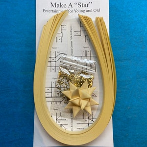 May include: A kit for making a paper star, with instructions and yellow paper strips. The kit includes a small bag of gold glitter.