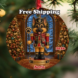 May include: A round Christmas ornament featuring a German Shepherd dressed as a nutcracker in a red and gold uniform with a plaid scarf. The design includes a paw print staff, the text 2026, and the name Aeris printed on a base.
