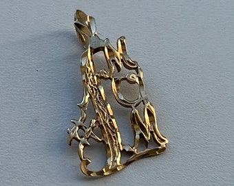 May include: A gold-colored pendant with a cursive letter 'M' design. The pendant is made of a textured metal and has a delicate, intricate design.