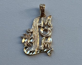 May include: Gold pendant necklace charm with the word "MOM" in a cursive script.