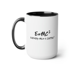 May include: White ceramic coffee mug with a black handle and rim. The mug features the equation E=MC² and the humorous phrase "ENERGY = MILK X COFFEE²" in black text. A fun and quirky gift for science enthusiasts and coffee lovers.