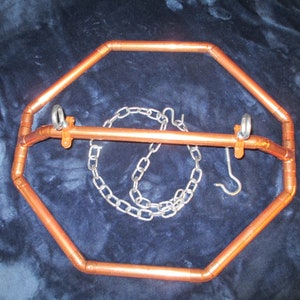 May include: A copper-colored metal frame with a chain and hook. The frame is octagonal and has a horizontal bar across the top.