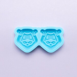 May include: A light blue silicone mold with two bear face shapes. The mold is designed for making resin crafts.