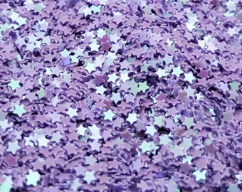 May include: A close-up of a pile of purple star-shaped glitter. The glitter is iridescent and has a light blue sheen.
