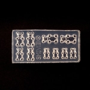 May include: A clear plastic mold with the word "SHINEIR" printed on it. The mold is shaped like a sheet of gummy bears. There are 9 gummy bear shapes in the mold.