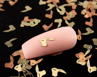 May include: A pink false nail with a gold metal accent in the shape of a rabbit head.