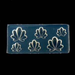May include: A clear silicone mold with six raised designs of stylized fan shapes. The mold is designed for nail art and crafting.