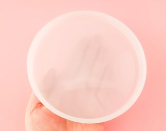 May include: A clear silicone mold for making resin crafts. The mold is round and has a smooth surface.
