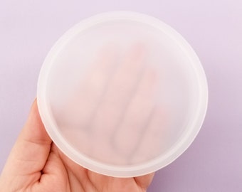 May include: A clear, round silicone mold for resin crafts. The mold is flexible and has a smooth, glossy finish.