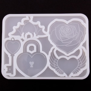 May include: White silicone mold with six different heart-shaped designs: a key, a padlock, a rose, a bat, and two winged hearts.