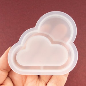 May include: A clear silicone mold shaped like a cloud with a smaller cloud inside. The mold is designed for making resin crafts.