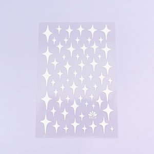 May include: A sheet of clear plastic with a white background. The sheet is covered in white star stickers. The sheet has the text "R424" printed in the bottom right corner.