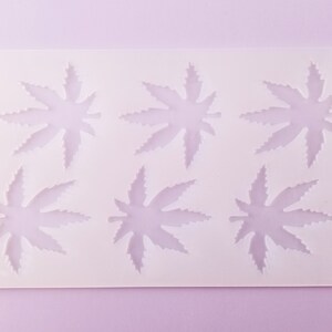 May include: White silicone mold with six leaf-shaped cavities. The mold is designed for making chocolate or candy.