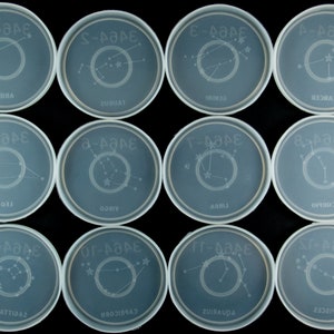 May include: Twelve clear plastic petri dishes with constellation outlines and names, including Aries, Taurus, Gemini, Cancer, Leo, Virgo, Libra, Scorpio, Sagittarius, Capricorn, Aquarius, and Pisces.