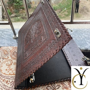 May include: A dark brown leather binder featuring an embossed tree design on the front cover, intricate braided leather edges, and a metal latch closure. The interior contains a black fabric lining and a metal ring mechanism for securing documents.