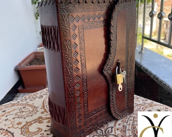 Può includere: Un diario in pelle marrone scuro, fatto a mano, con intricati disegni in rilievo e una chiusura sicura. Il diario presenta motivi dettagliati lungo i bordi e il dorso, con un lucchetto per la privacy. La copertina è di un marrone ricco e lucido.