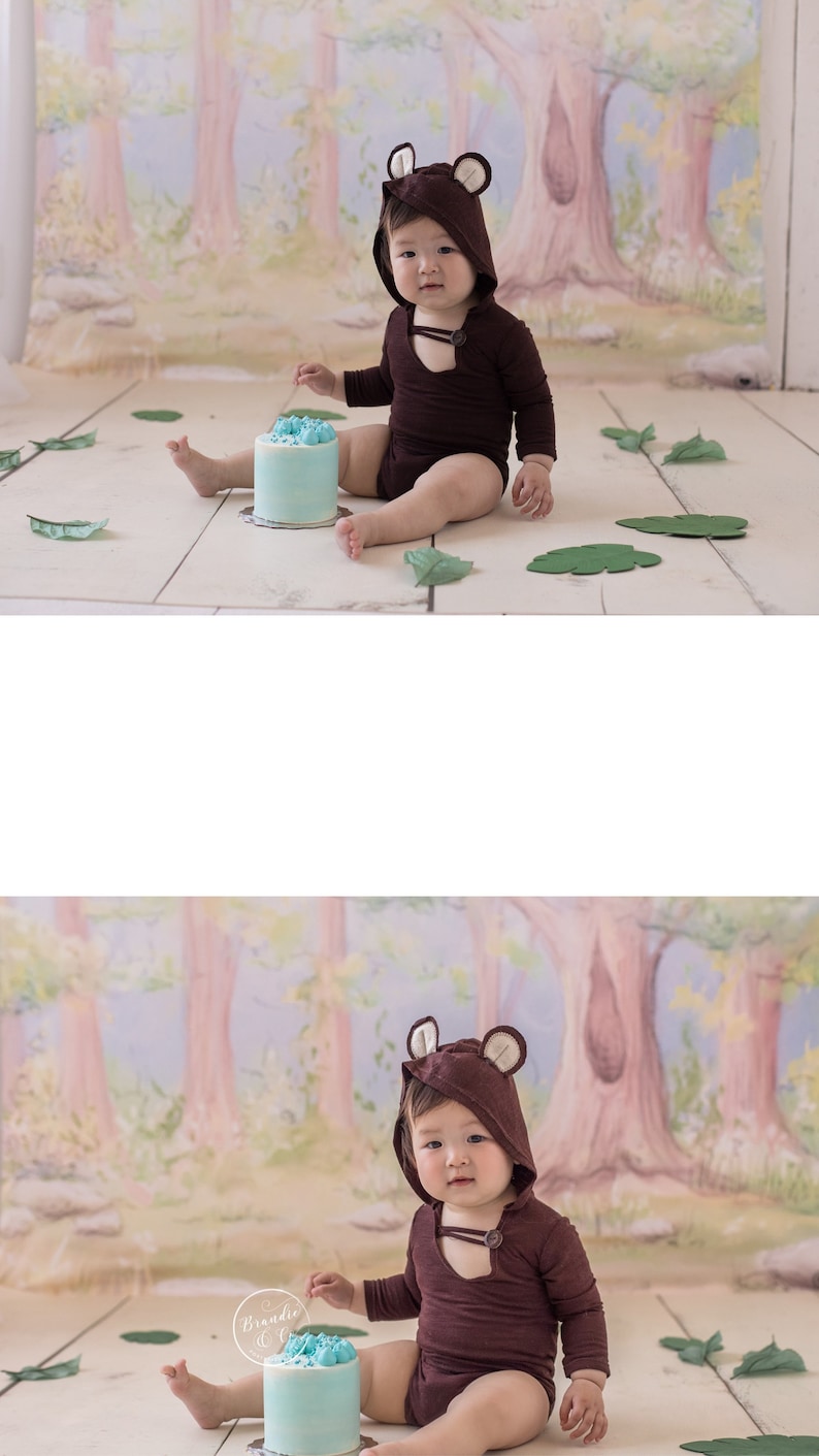 May include: A baby wearing a brown bear costume sits on a white floor with a blue and white cake in front of them. The cake has a white topper with the text "Brandie & Co."