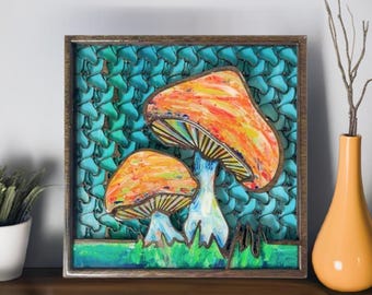 May include: A framed artwork featuring two brightly colored mushrooms with orange and yellow caps and white stems against a turquoise background. The mushrooms are painted in a stylized, almost psychedelic way.