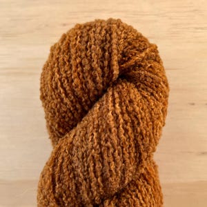 May include: A skein of brown yarn with a fuzzy texture.