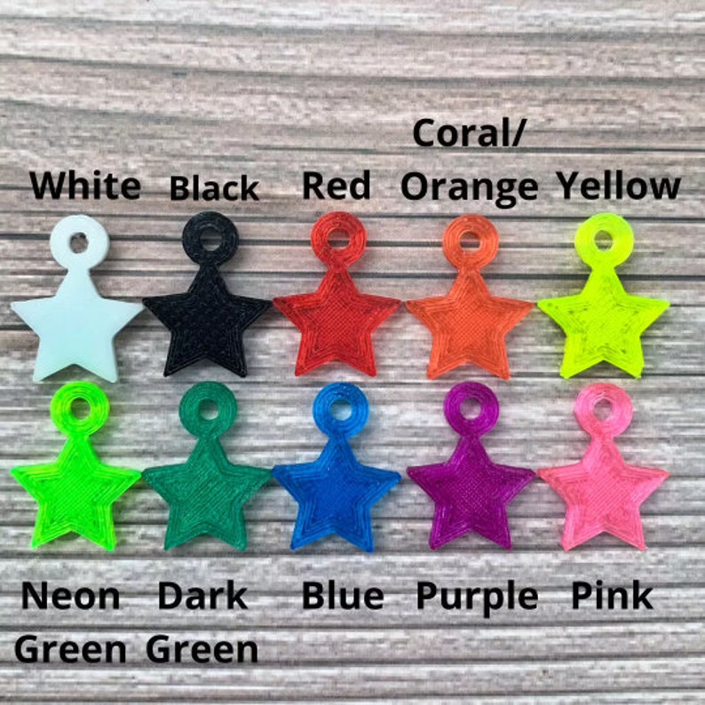 May include: A set of 10 star-shaped charms in various colors, including white, black, red, orange, yellow, neon green, dark green, blue, purple, and pink. The charms are arranged in two rows, with the colors labeled below each row.