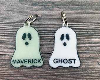 May include: Two white ghost-shaped keychains with black eyes and mouths. One keychain says "Maverick" and the other says "Ghost".
