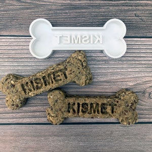 Peut inclure: Deux biscuits pour chien en forme d'os avec le mot "Kismet" imprimé dessus. Un emporte-pièce en plastique blanc en forme d'os avec le mot "Kismet" imprimé dessus est également présenté.