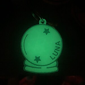 May include: A green glow-in-the-dark keychain shaped like a crystal ball with the word "LUNA" and two stars on it.