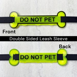 May include: A double-sided leash sleeve with the text "DO NOT PET" in black on a neon green background. The sleeve is designed to attach to a black leash. The words "Front" and "Back" are also visible.