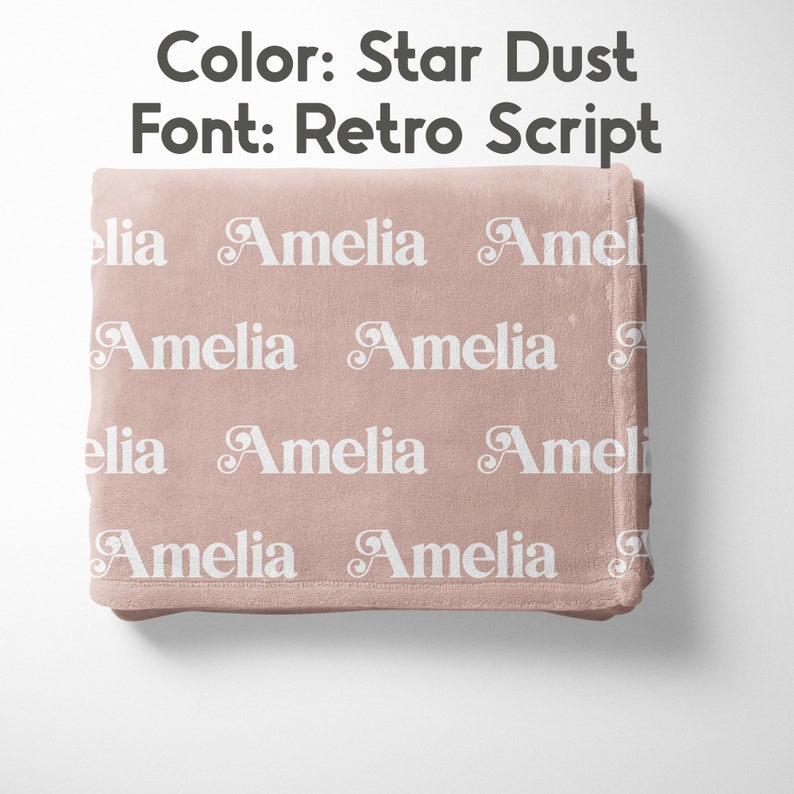 May include: A soft, star dust-colored blanket with the name "Amelia" repeated in white, using a retro script font. The blanket is folded neatly, showcasing the design. The text "Color: Star Dust" and "Font: Retro Script" are visible.