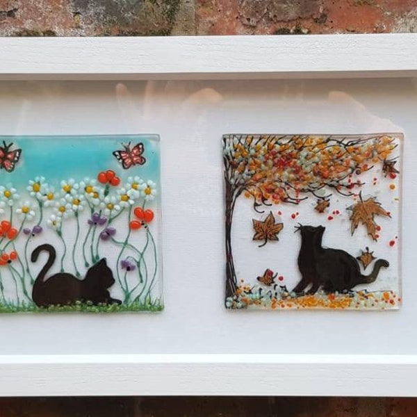 A cat for all seasons. Framed art. Black cat. Fused glass panels. four glass art pictures. White box frame. spring. Summer. Autumn. Winter.