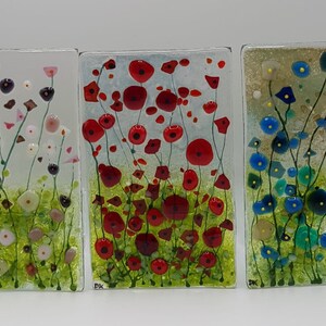 May include: Three rectangular glass panels with a floral design. The first panel features pink and white flowers with green stems. The second panel features red flowers with green stems. The third panel features blue flowers with green stems.