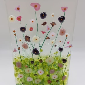 May include: A glass panel with a colorful floral design. The flowers are pink, white, and green. The background is clear glass.